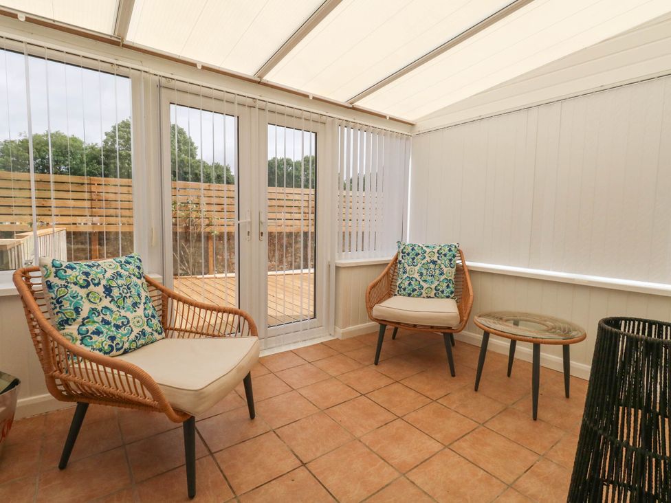 A conservatory with two chairs and a table at Greenwich Cottage in Burton Bradstock