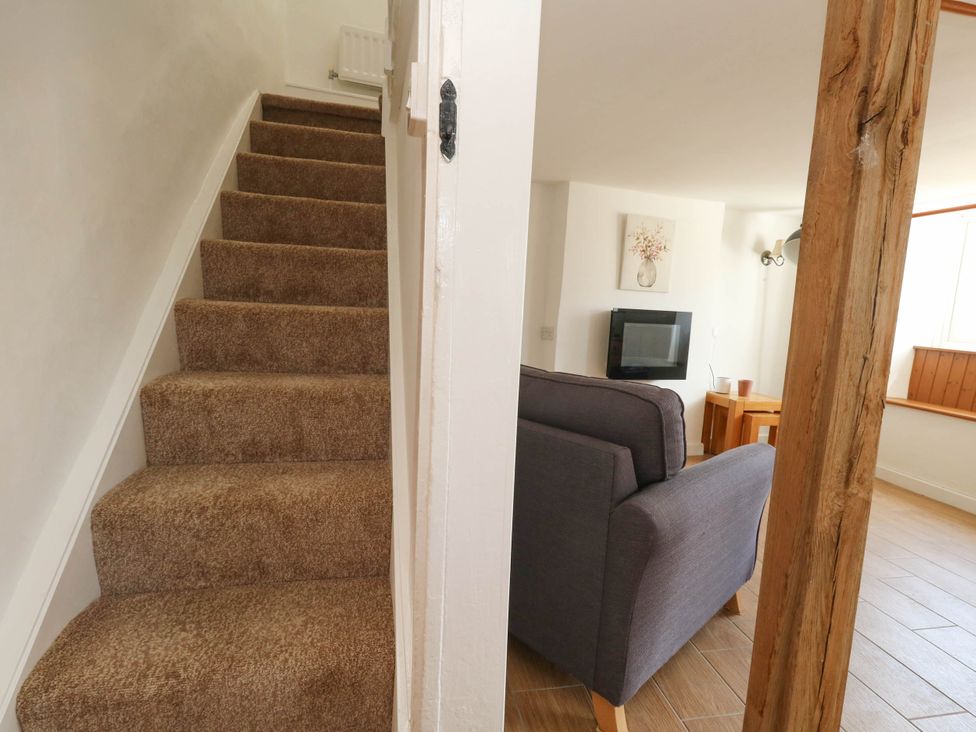 A living room with a sofa and television at Greenwich Cottage in Burton Bradstock
