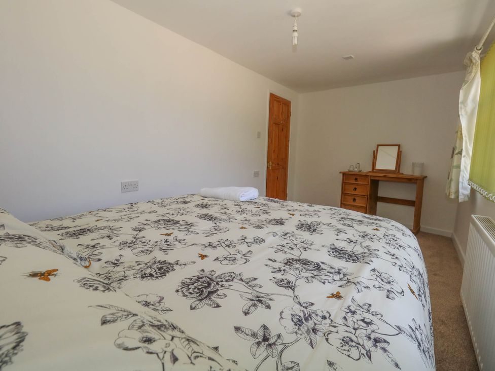 A bedroom with a bed and dresser at Greenwich Cottage in Burton Bradstock