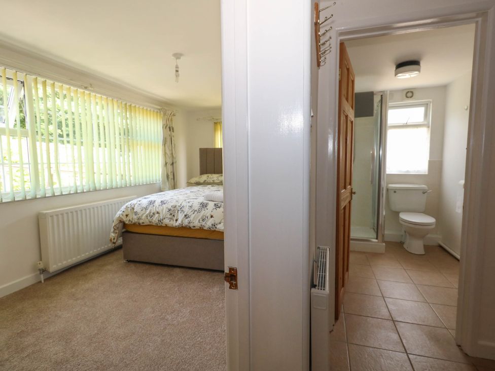 A bedroom with a bed and adjoining bathroom at Greenwich Cottage in Burton Bradstock