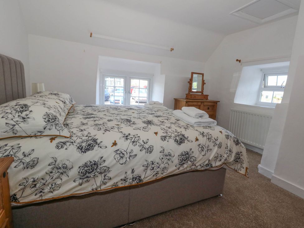 A bedroom with a bed, chest of drawers and mirror at Greenwich Cottage in Burton Bradstock