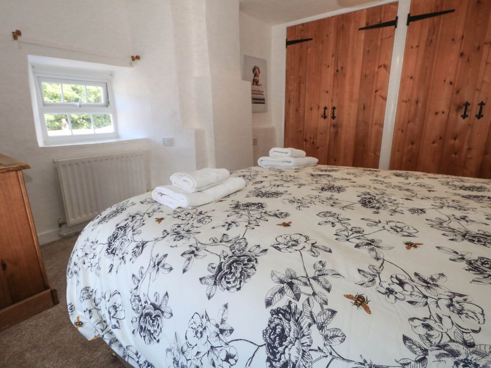 A bedroom with a bed covered in floral bedding at Greenwich Cottage in Burton Bradstock