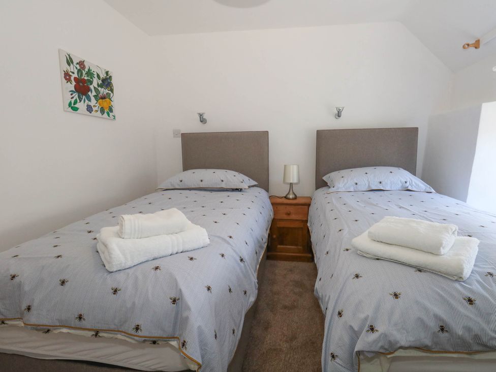 A bedroom with twin beds and a nightstand at Greenwich Cottage in Burton Bradstock