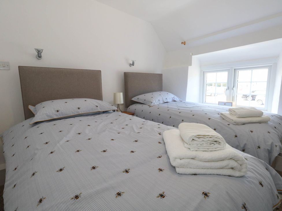 A bedroom with two beds and a window at Greenwich Cottage in Burton Bradstock