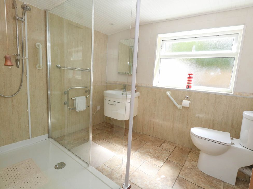 A bathroom with a shower, toilet, and sink at Greenwich Cottage in Burton Bradstock