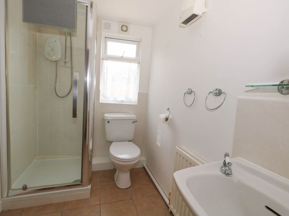 A bathroom with a shower, toilet, and sink at Greenwich Cottage in Burton Bradstock