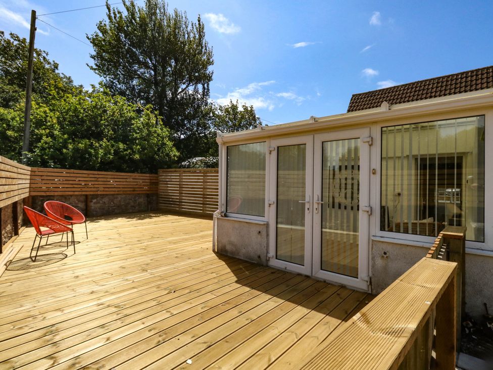 A garden area with decking and red chairs at Greenwich Cottage in Burton Bradstock
