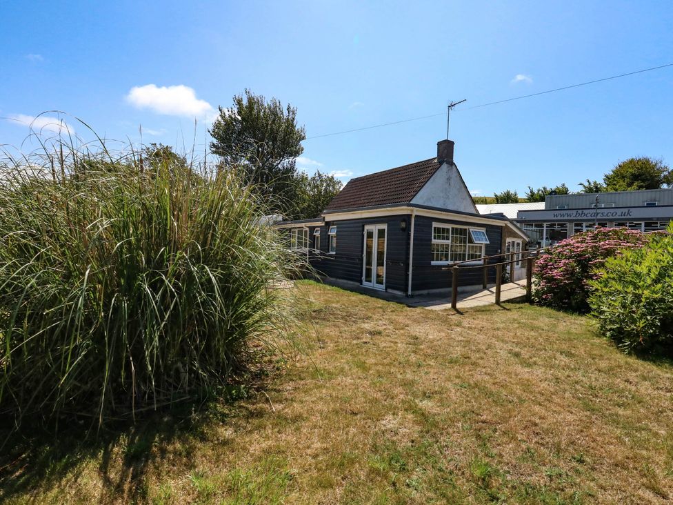 A house with surrounding grass and plants at Greenwich Cottage in Burton Bradstock