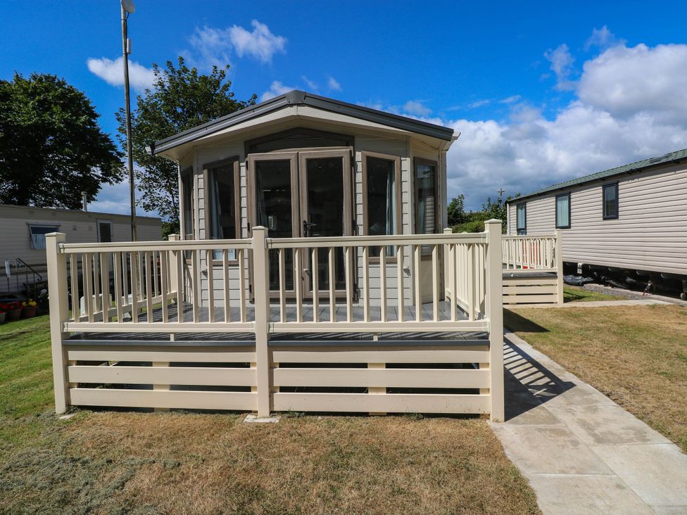 A deck area with a caravan in the background at Number 19 Ferryside