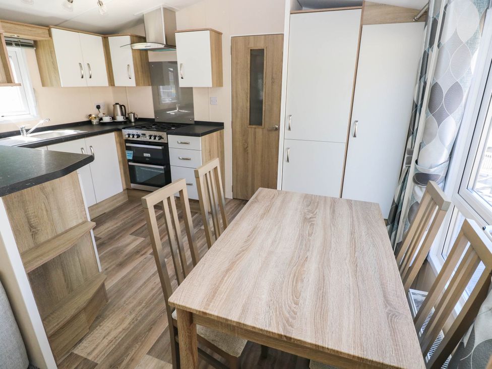 A kitchen with a dining table and chairs at Number 19 in Ferryside