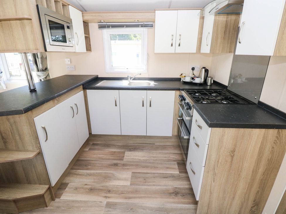 A kitchen with a sink, stove, and microwave at Number 19 Ferryside