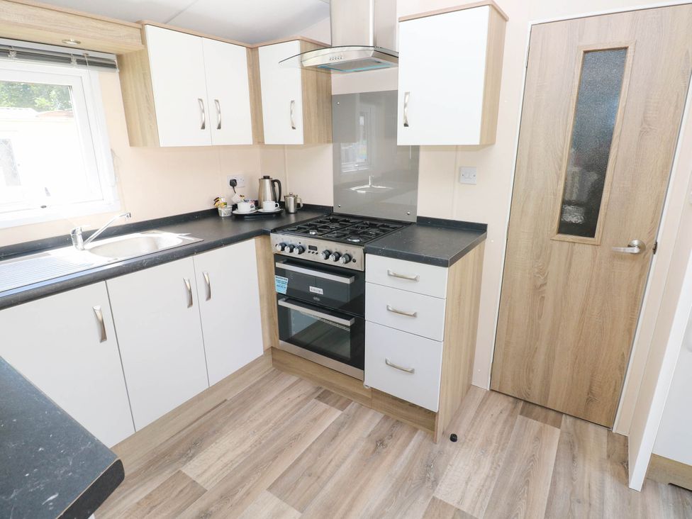 A kitchen with stove and sink at Number 19 Ferryside