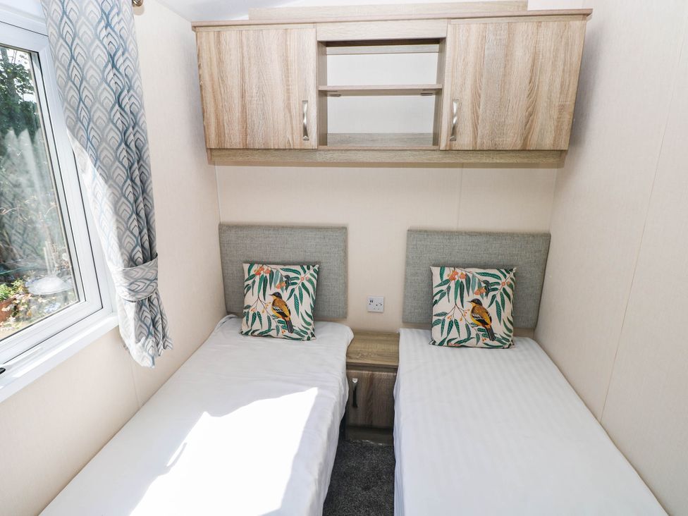 A bedroom with two single beds and a shelf at Number 19 in Ferryside