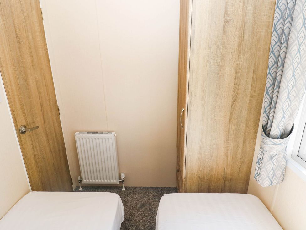 A bedroom with two beds and a wardrobe at Number 19 in Ferryside