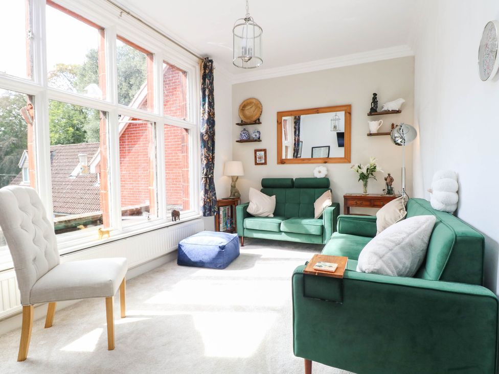 A living room with a green sofa and a mirror at 10 Uplands Court in Brundall