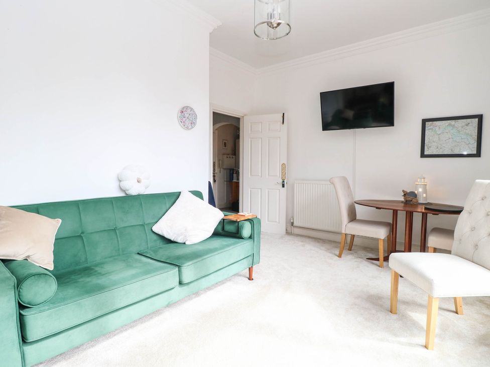 A living room with a green sofa and a dining table at 10 Uplands Court in Brundall