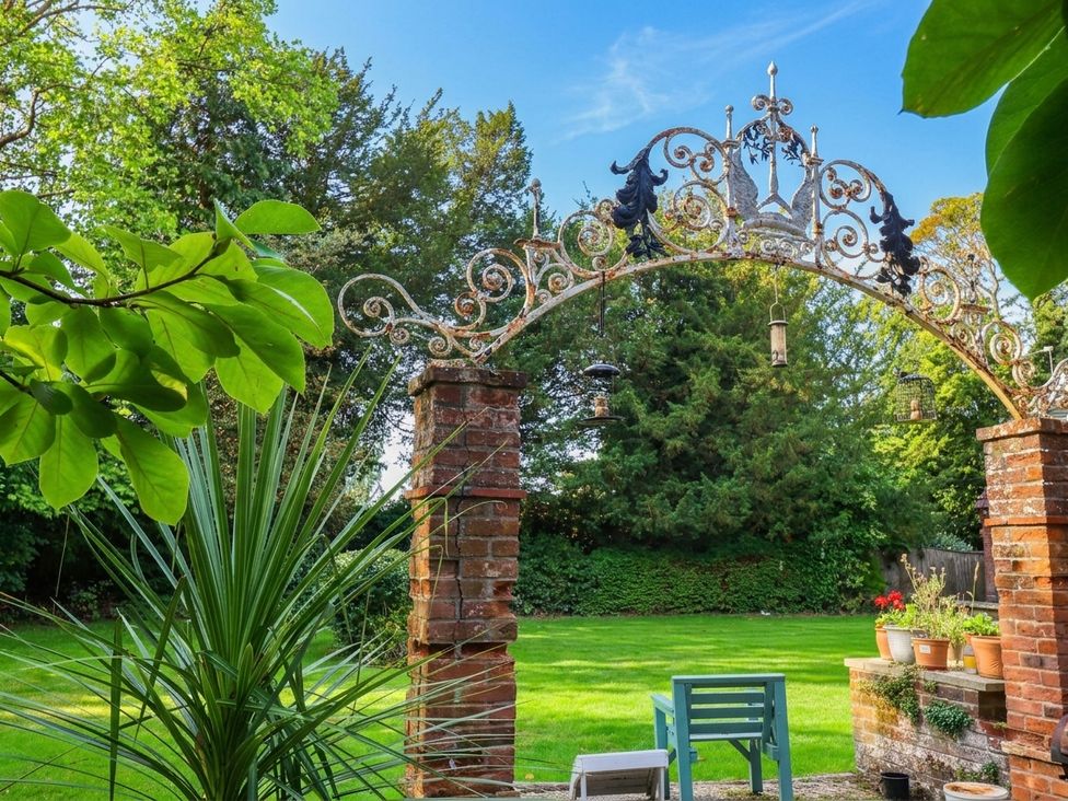 A garden with an archway and flower pots at 10 Uplands Court in Brundall