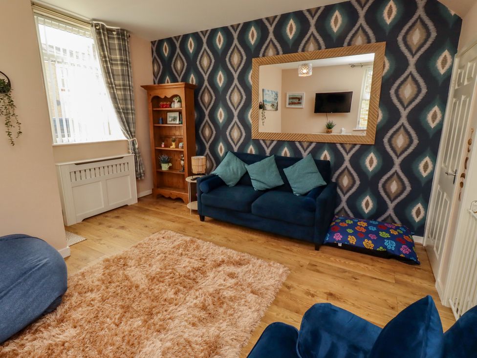 A living room with a sofa, bookshelf and mirror at The Old Bank House Red Row near Amble