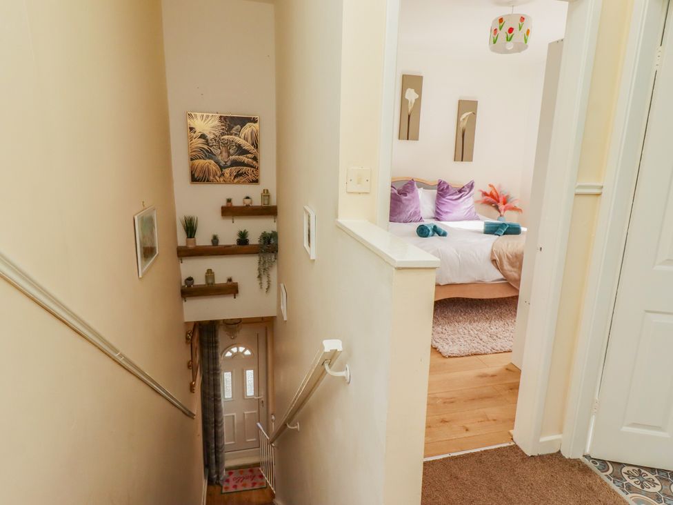 A hallway with a staircase and a door leading to a bedroom at The Old Bank House Red Row near Amble