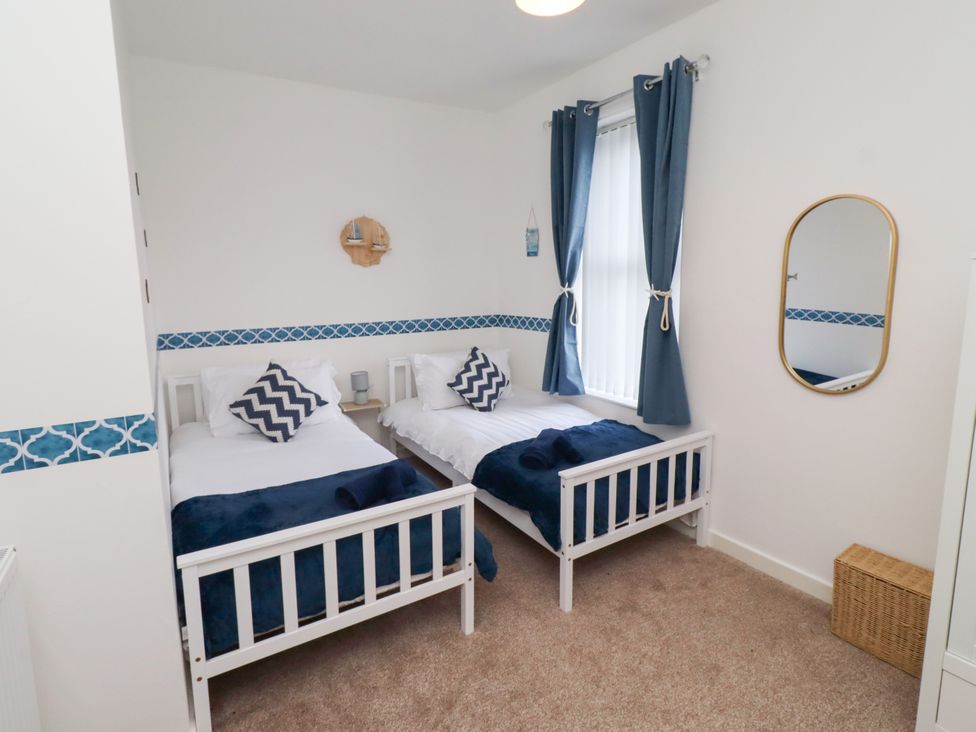 A bedroom with two beds and a mirror at The Old Bank House Red Row near Amble