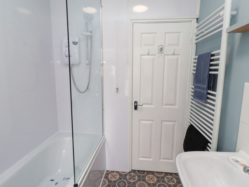 A bathroom with a bathtub shower and sink at The Old Bank House Red Row near Amble