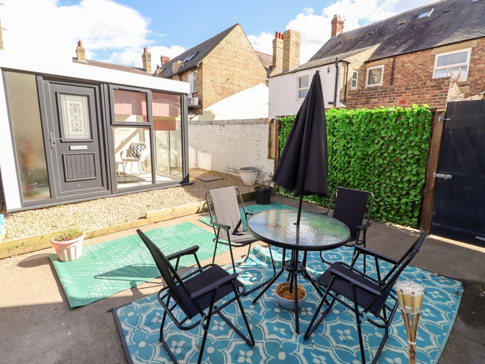 An outdoor seating area with a table and chairs at The Old Bank House in Red Row near Amble