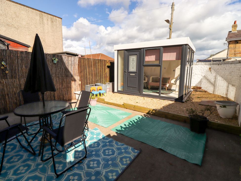 A garden with a table, chairs, and a garden room at The Old Bank House Red Row near Amble