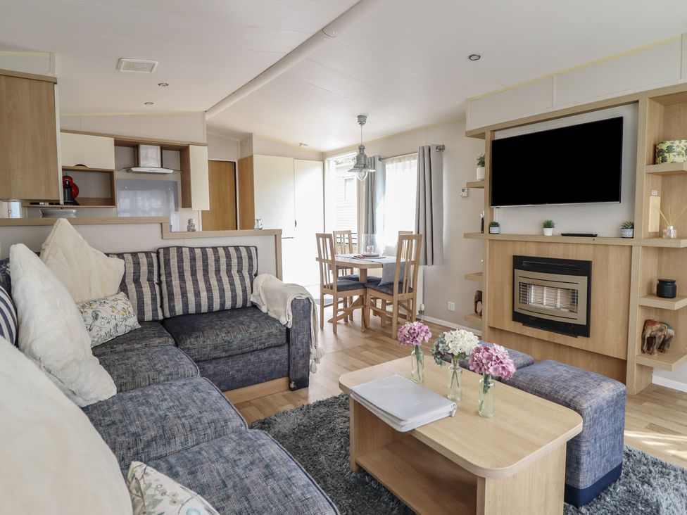 A living room with a sofa and dining area at Plot 13A