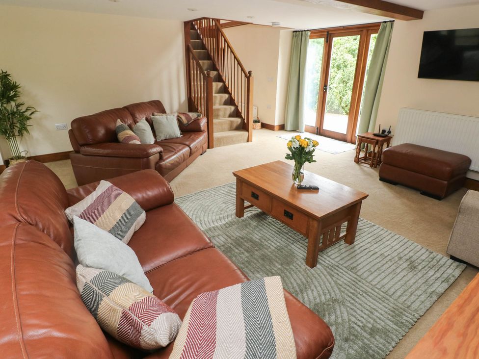 A living room with a sofa, coffee table, and stairs at Penrhiwoli Barn in Cefn Gorwydd