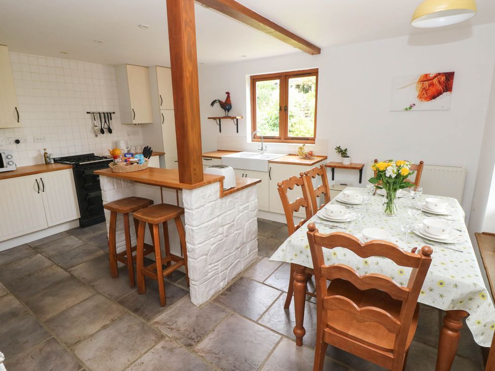 A kitchen with stools and dining table at Penrhiwoli Barn Cefn Gorwydd