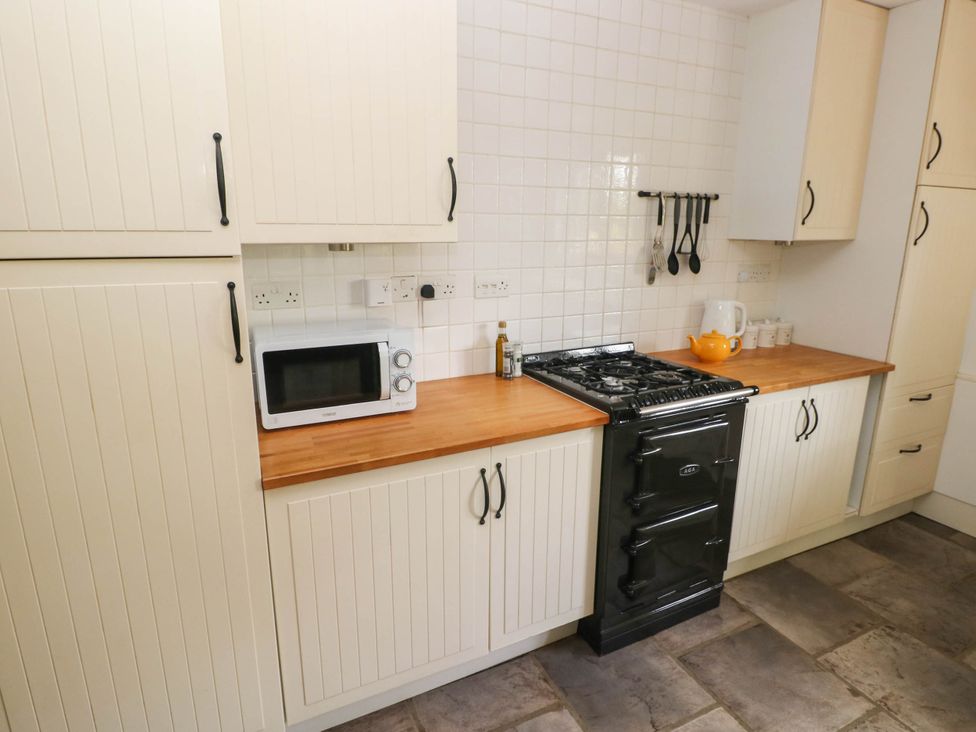 A kitchen with a gas cooker and microwave at Penrhiwoli Barn Cefn Gorwydd