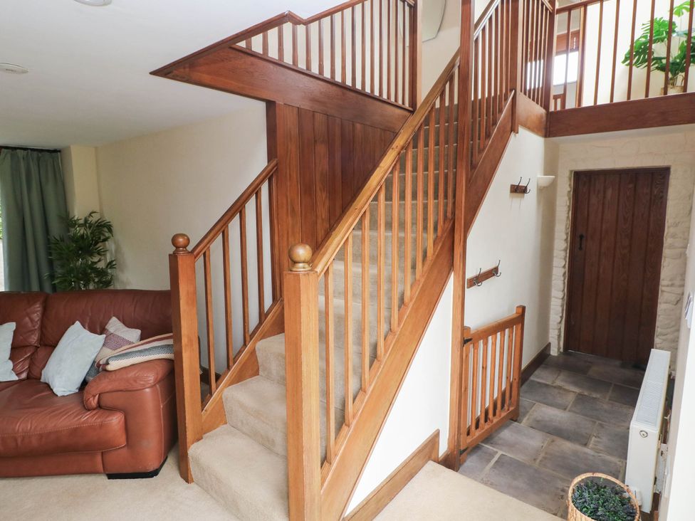 A hallway with a staircase and sofa at Penrhiwoli Barn Cefn Gorwydd