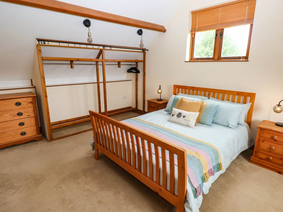 A bedroom with a bed and wardrobe at Penrhiwoli Barn in Cefn Gorwydd
