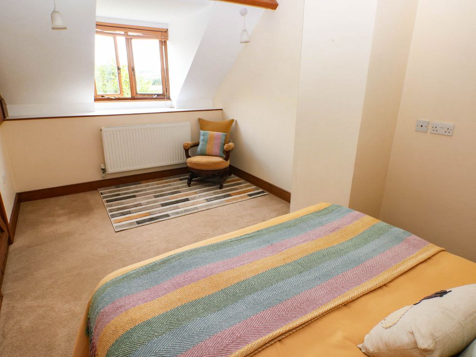 A bedroom with a bed and chair at Penrhiwoli Barn Cefn Gorwydd