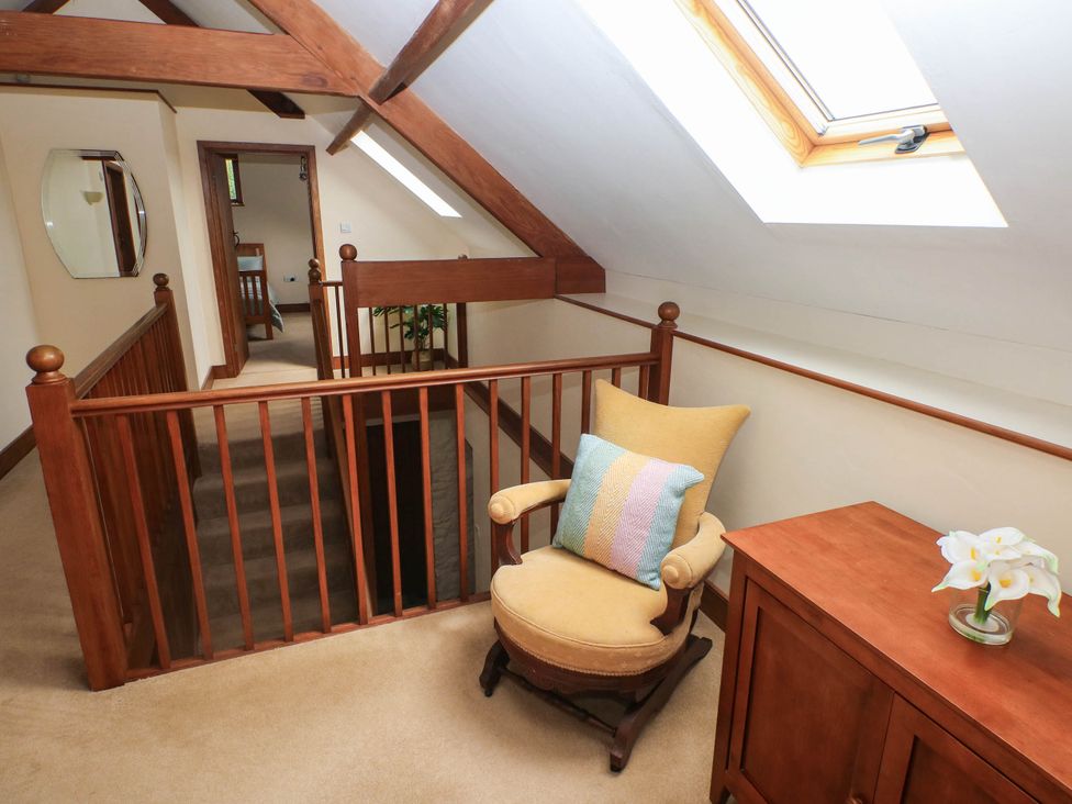 A landing area with a chair and table at Penrhiwoli Barn in Cefn Gorwydd