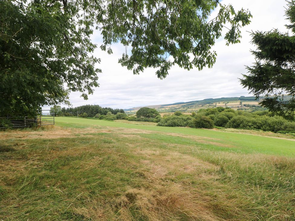 A landscape view with grass and trees at Penrhiwoli Barn in Cefn Gorwydd