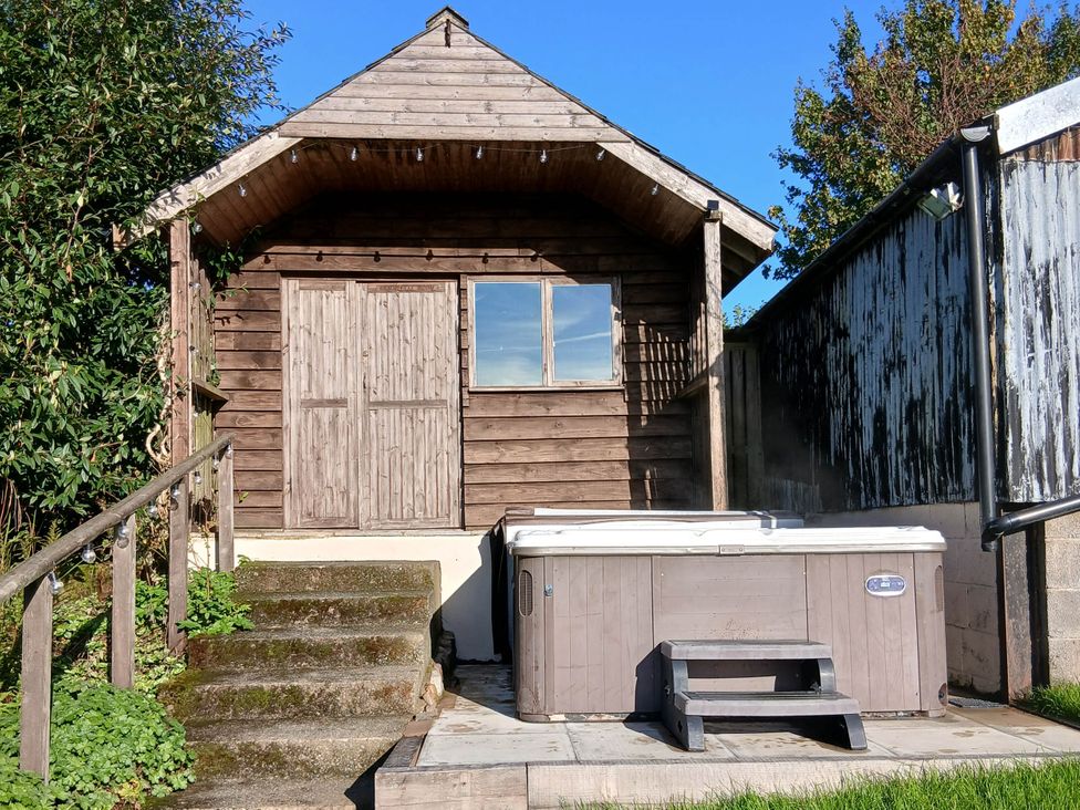 A hot tub in front of a wooden shed at Penrhiwoli Barn Cefn Gorwydd