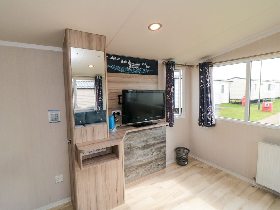 A living room with a television and a mirror at 42 Oak Green