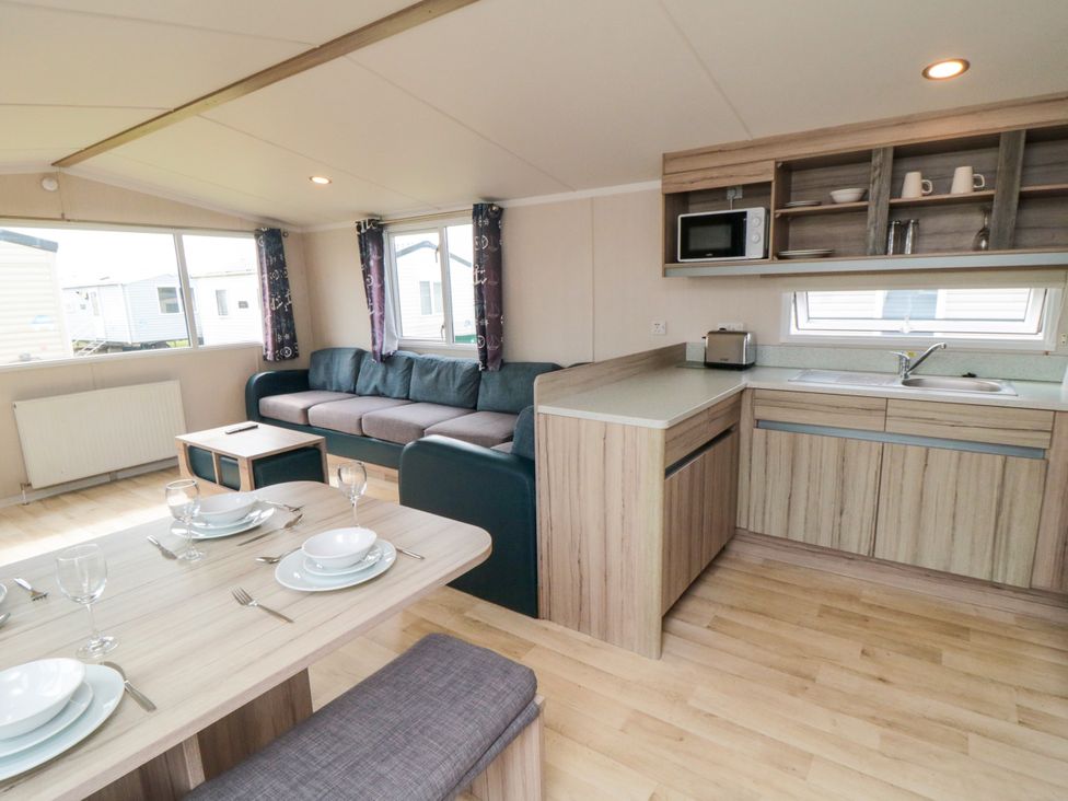 A living room with a kitchen area and dining table at 42 Oak Green 