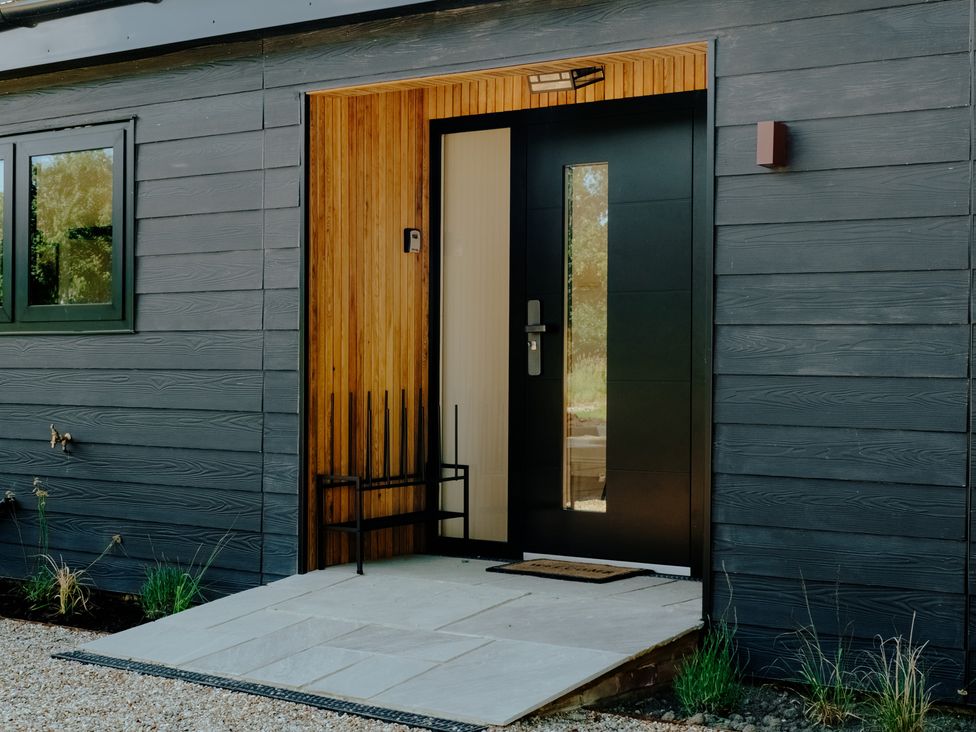 An entrance with a black front door and gravel pathway at Baldslow Barn Battle near Hastings