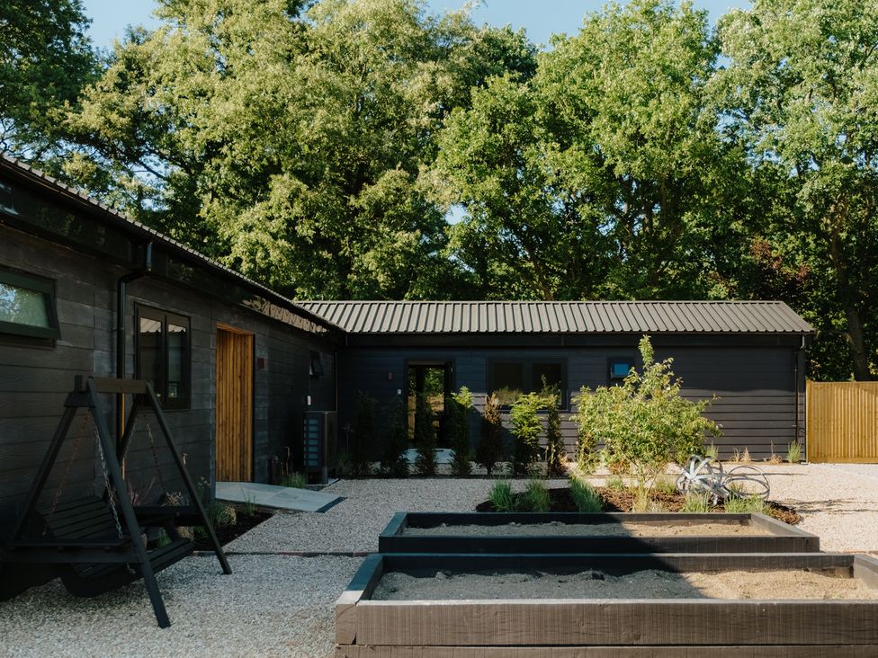 A garden area with a swing and plant beds at Baldslow Barn Battle near Hastings