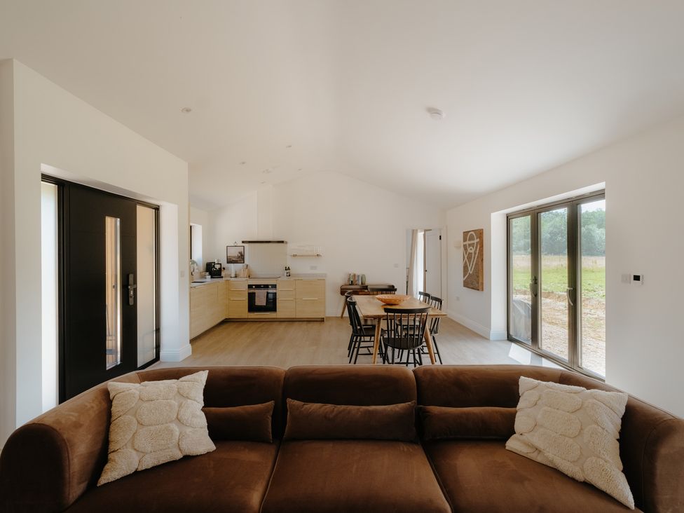 A living room with a sofa and dining area at Baldslow Barn in Battle near Hastings