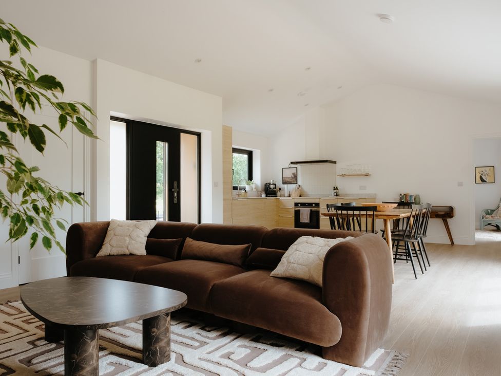 A living room with a sofa and dining area at Baldslow Barn in Battle near Hastings