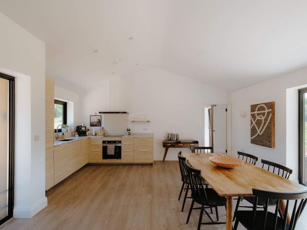 A kitchen with a dining table and black chairs at Baldslow Barn in Battle near Hastings