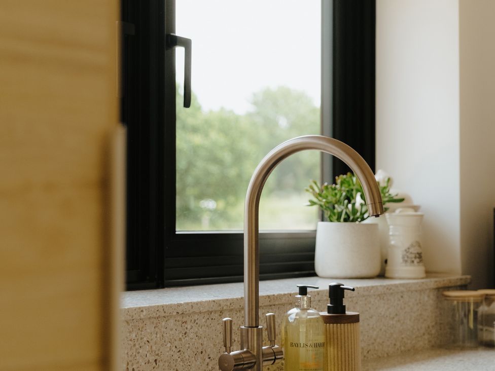 A kitchen with a tap and sink in front of a window at Baldslow Barn in Battle near Hastings