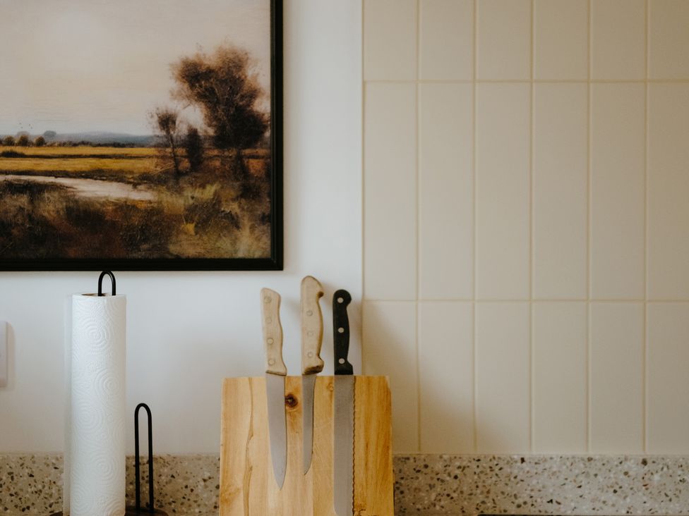 A kitchen with knives on a cutting board and a painting on the wall at Baldslow Barn near Hastings