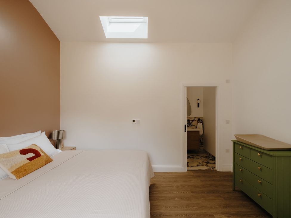 A bedroom with a bed and a door leading to a bathroom at Baldslow Barn near Hastings