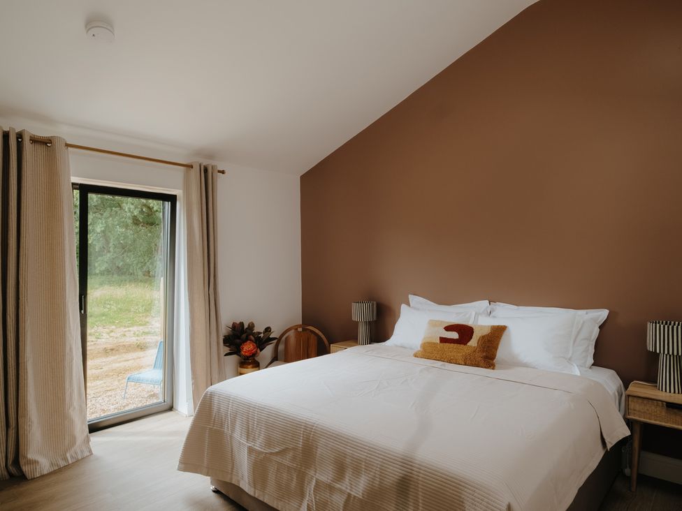A bedroom with a bed and curtains at Baldslow Barn in Battle near Hastings