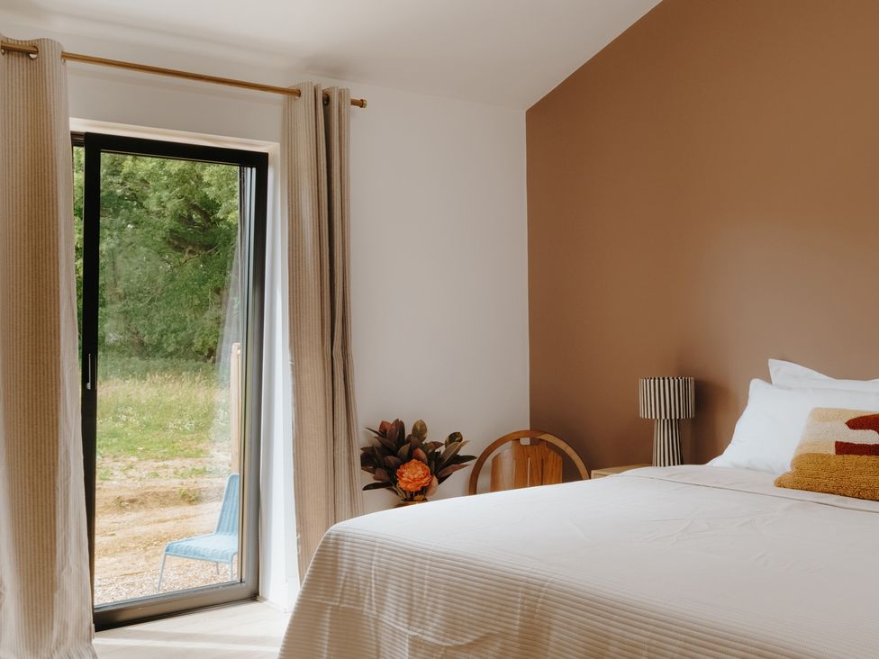 A bedroom with a bed and a chair at Baldslow Barn near Hastings