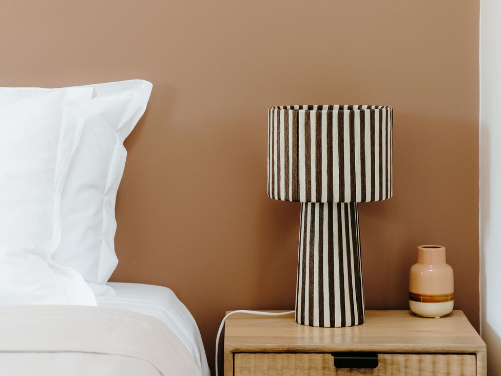 A bedroom with a lamp and a vase on a nightstand at Baldslow Barn in Battle near Hastings